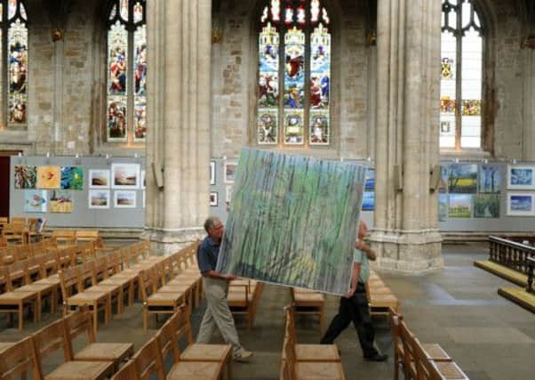 David Edwards (left) and Keith Askham carry a painting 'Young Willows'  oil on canvas by Michael Bilton down the aisle of Ripon Cathedral