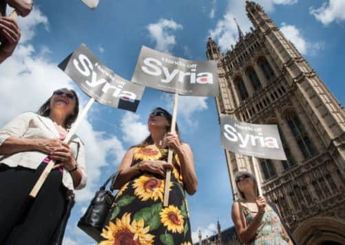 Protestors demonstrating against military action in Syria stand outside the Houses of Parliament