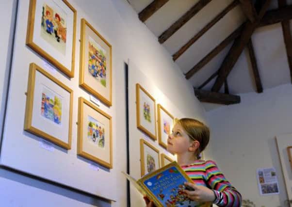 Madeline Roy, 8, from Long Marston near York, looks at Postman Pat pictures by artist Ray Mutimer