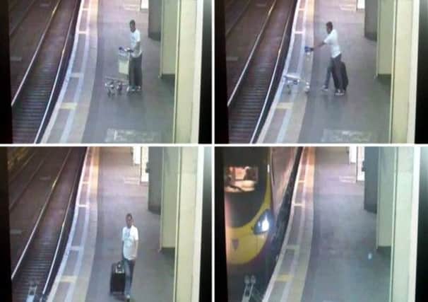 A man police would like to trace, pushing a suitcase trolley onto the tracks at Euston station in London.