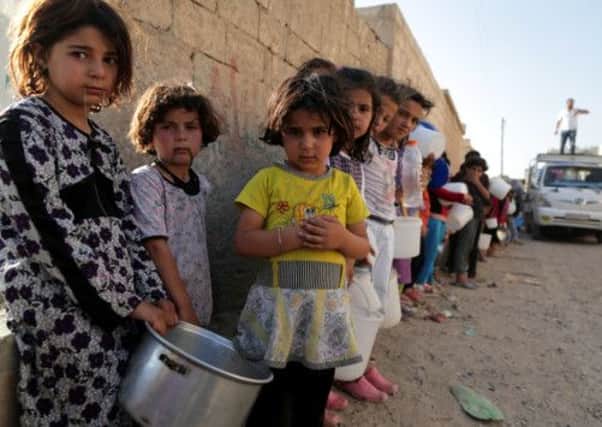 Syrian children wait in line to collect a free Iftar meal