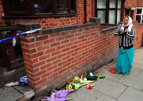 A local resident says a prayer outside the scene of a fatal house fire in Wood Hill, Leicester.