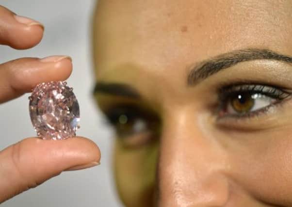 A Sotheby's employee shows The Pink Star diamond weighing 59.6 carat, during a preview at  Sotheby's in Geneva