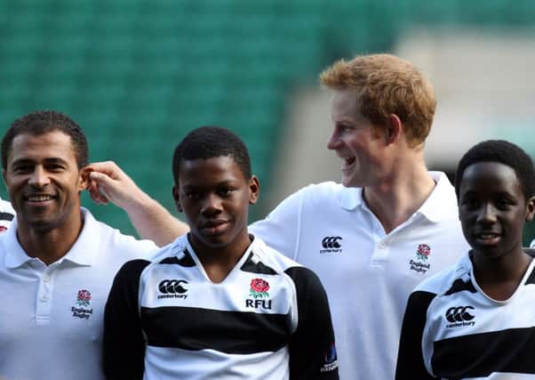 Prince Harry pulls the ear of Jason Robinson as they take a coaching session for youngsters at Twickenham