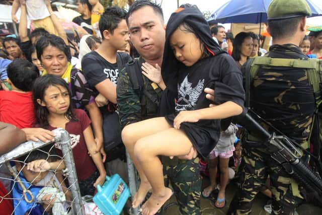 Thousands of typhoon survivors swarmed the airport on Tuesday seeking a flight out, but only a few hundred made it, leaving behind a shattered, rain-lashed city short of food and water and littered with countless bodies.