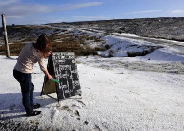 A woman beats the freeze as she clears the snow off signs for the Tan Hill Inn, on the Pennine tops above Reeth in Swaledale. PIC: PA