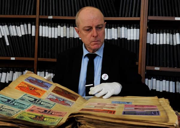 Archivist Dr Charles Kelham looks at a collection of 19th century race tickets from Doncaster Racecourse.