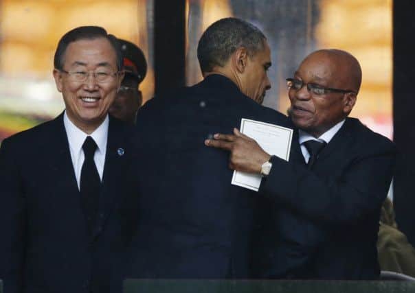U.N. Secretary General Ban Ki-moon, left, watches as President Barrack Obama hugs South African President Jacob Zuma, right during the memorial service for former South African president Nelson Mandela