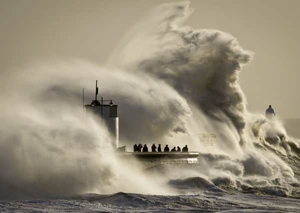 People watch and photograph enormous waves as they break on Porthcawl harbour, South Wales, and flooded Hebden Bridge, below.