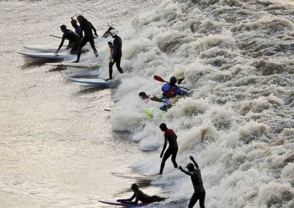 Surfers, kyakers and wave-skiers ride the tidal Severn Bore as it passes Newnham, Gloucestershire.