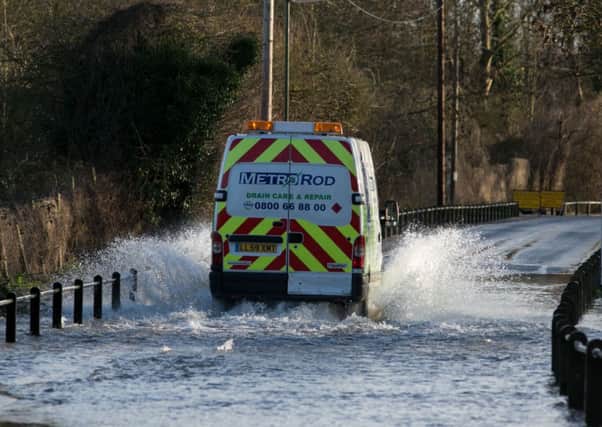 A van drives through a flooded road next to the River Thames in Chertsey, Surrey.