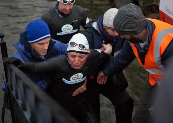 Davina McCall on Day 3 of her Sport Relief Challenge is helped from the water as she completes her swim across Lake Windermere.