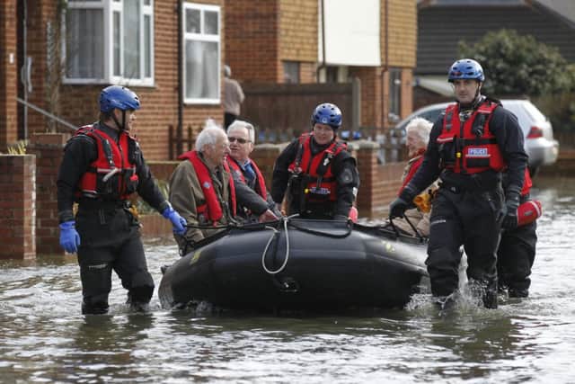 Sussex Police Search and Rescue officers evacute residents through to a flooded street in Egham