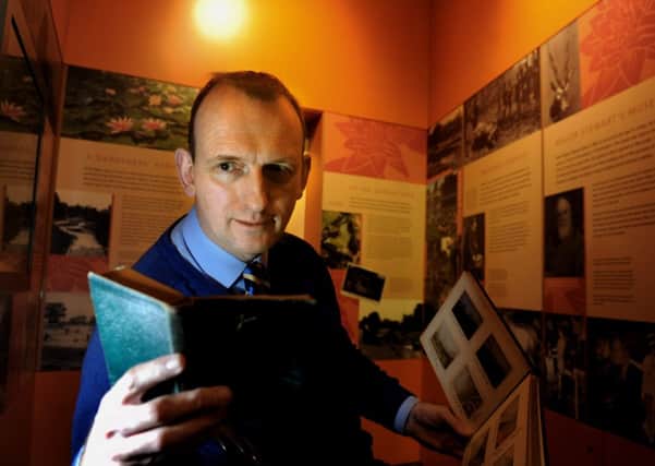 Peter Rogers looking at the diary and photo album of Herbert Stewart in the Stewart Museum at Burnby Hall Gardens  at Pocklington