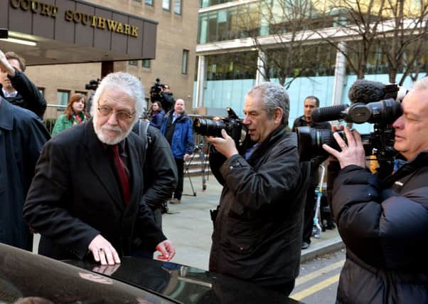 An emotional Dave Lee Travis battles through the waiting media outside Southwark Crown Court, in south London