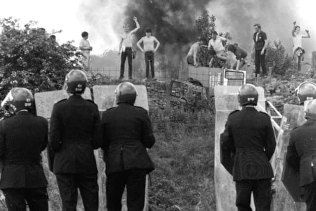 1984: Anti-riot squad police watching as pickets face them against a background of burning cars at the Orgreave coke works, Yorkshire.