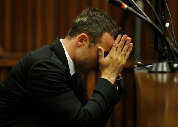 Oscar Pistorius sits with his head in his hands in the dock on the third day of his trial at the high court in Pretoria