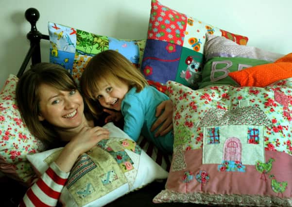 Lucy Philips with her daughter Belle under a pile of cushions  she makes at home.