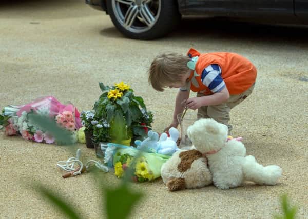 Members of the public lay flowers at a house in New Malden, south London, after a woman was arrested following the discovery of three dead children at the address.