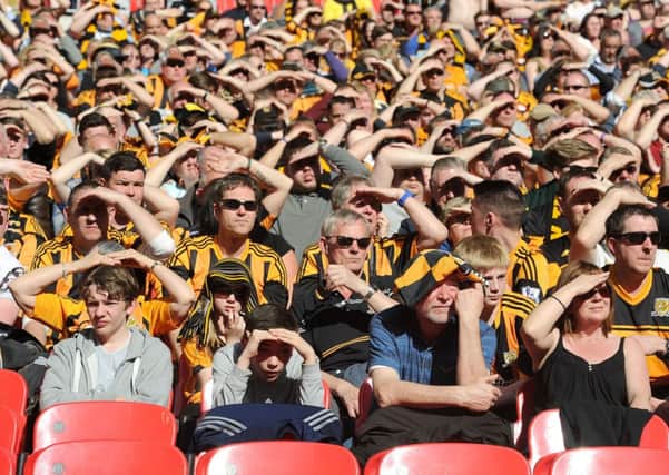 Hull City fans shield their eyes from the sun in the stands during the FA Cup Semi Final match at Wembley Stadium.
