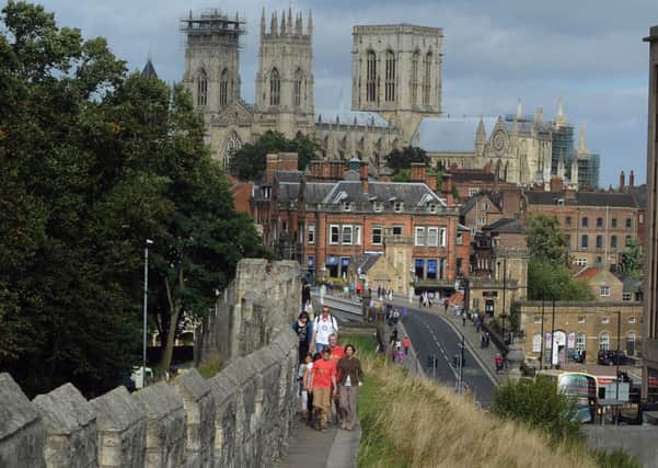 Visitors to York walk along the city walls of York, with York Minster as a backdrop. Picture by Gerard Binks