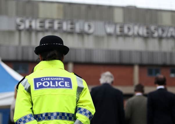 A police officer stands in front of members of the press outside the Hillsborough stadium in Sheffield