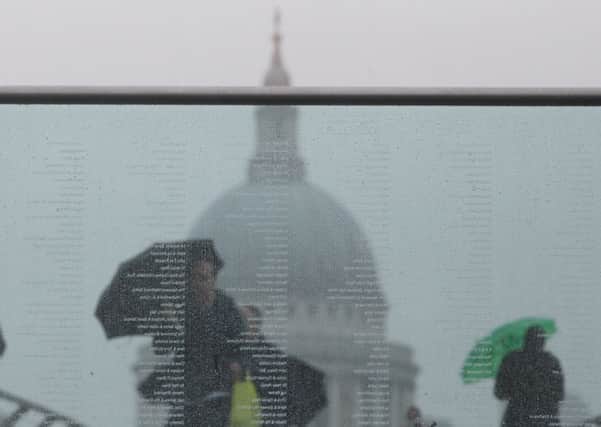 Tourists are seen through glass during wet weather on the Millennium Bridge, London.