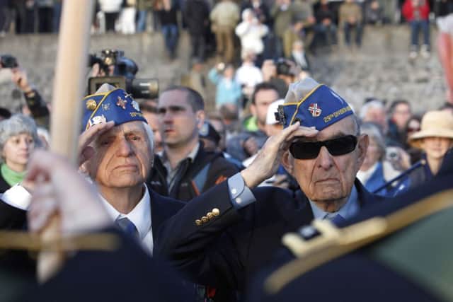 World War II veterans of the U.S. 29th Infantry Division, Hal Baumgarter, right, 90, Pa., and Steve Melnikoff, 94, R.I., salute during a D-Day commemoration, on Omaha Beach in Vierville sur Mer, western France , Friday June 6, 2014. Veterans and Normandy residents are paying tribute to the thousands who gave their lives in the D-Day invasion of Nazi-occupied France 70 years ago. (AP Photo/Thibault Camus)
