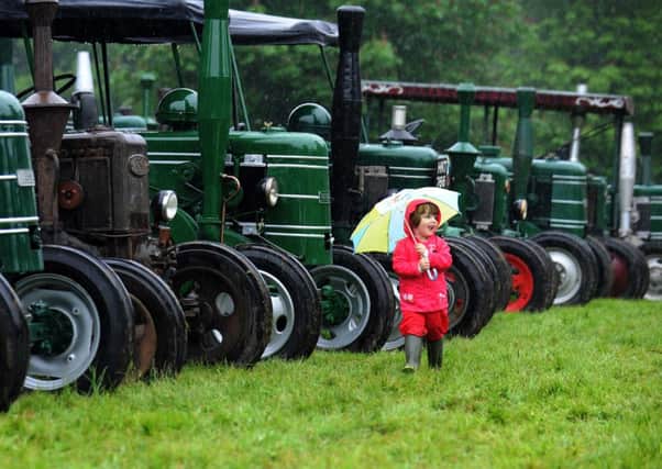 Three-year-old Molly Anne Holden from Wakefield shelters from the rain at the Tractor Fest event at Newby Hall, near Ripon.
 Picture: Jonathan Gawthorpe.