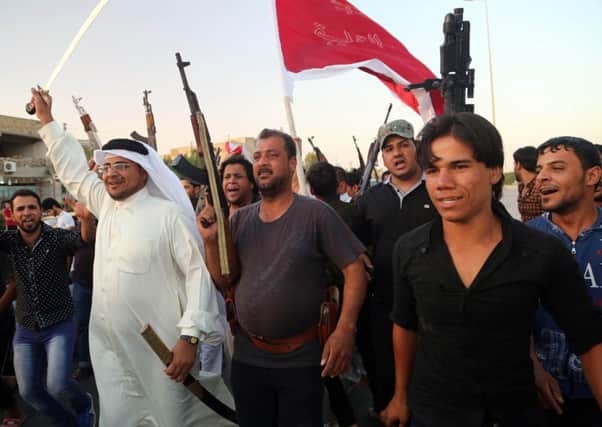 Shiite tribal fighters raise their weapons and chant slogans against the al-Qaida-inspired Islamic State of Iraq and the Levant (ISIL) in Basra