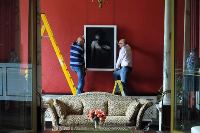 Emerson Mayers (right) and his father Trevor Mayers hang a pastel and collage art work by Mark Demsteader