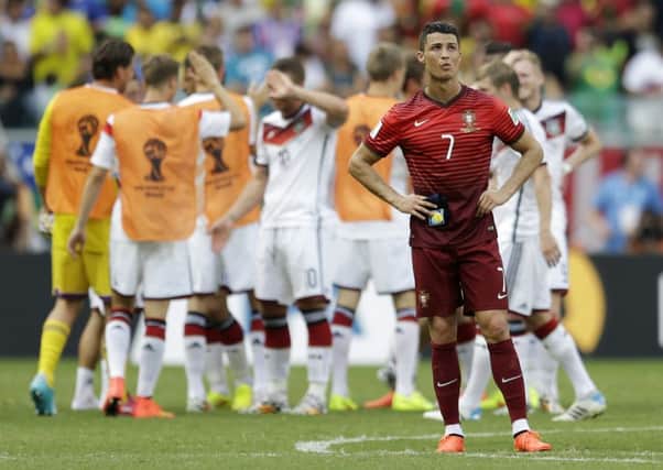 Portugal's Cristiano Ronaldo stands on the pitch as German players celebrate following Portugal's 4-0 loss to Germany.