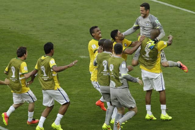 Brazil's goalkeeper Julio Cesar, top right, is congratulated by his teammates as Chile's Gonzalo Jara, top left, walks past after the World Cup round of 16 soccer match between Brazil and Chile at the Mineirao Stadium in Belo Horizonte