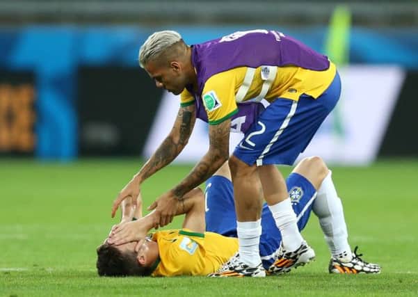 Brazil's Oscar (on floor) has to be consoled by teammate Dani Alves.