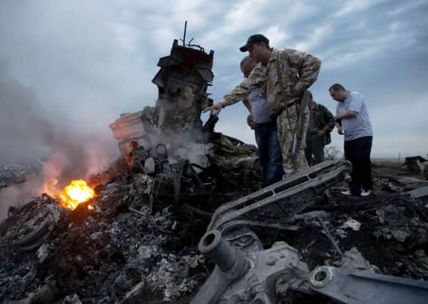 People inspect the crash site of a passenger plane near the village of  Hrabove, Ukraine