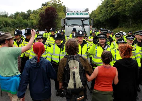 Police officers push back environmental activists as they slow down a lorry heading to the Cuadrilla exploratory drilling site in Balcombe, West Sussex
