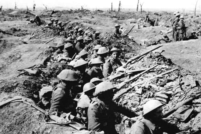 British infantrymen occupying a shallow trench in a ruined landscape before an advance during the Battle of the Somme.