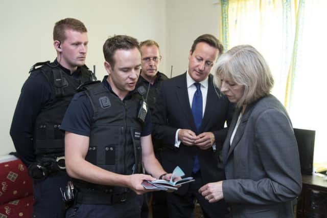 David Cameron and Home Secretary Theresa May speak to Home Office Immigration Enforcement officers at a property where six immigrants were arrested in Slough, Berkshire.