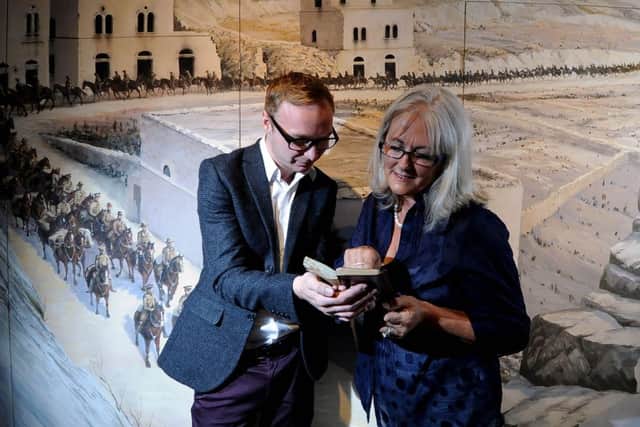 York Castle Museums Philip Newton examines diary, alongside volunteer Linda Bird, in front of a paint backdrop of Palestine during World War One.
