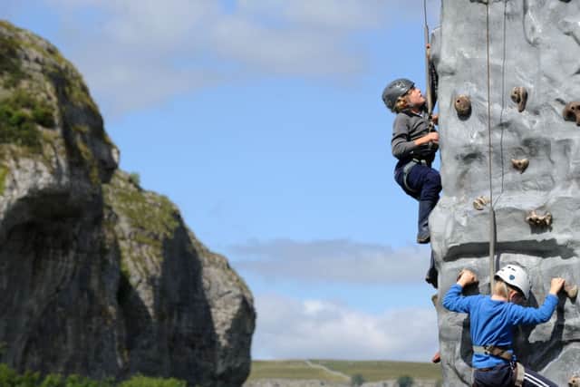 Children on an artificial climbing wall with Kilnsey Crag  in the background