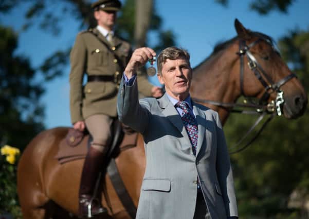 Brough Scott, grandson of Warrior's owner and rider General Jack Seely, shows off the Honorary PDSA Dickin Medal.