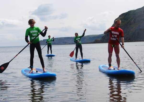 Luke Hutchinson, left, an associate of Whitby Surf School and its head Sam Pepler lead the paddleboarders to dry land.