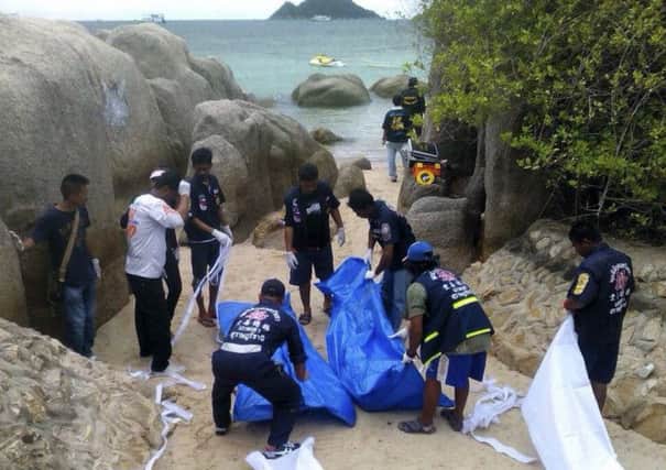 Thai officers work near the bodies of two British tourists on a beach in Surat Thani  province, southern Thailand.