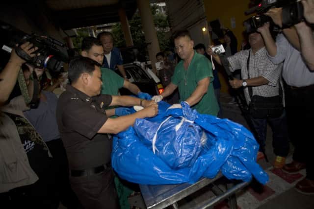 The body of British tourist David Miller, wrapped in a plastic sheet, is carried to a forensic police facility in Bangkok