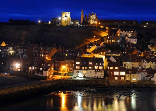 St Mary's Church and Whitby Abbey stand proud over Whitby at dusk descends.