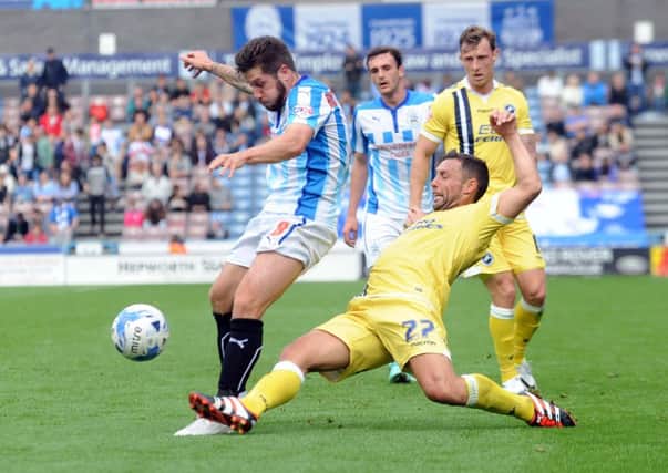 Huddersfield's Jacob Butterfield is challenged by Millwall player Scott McDonald.