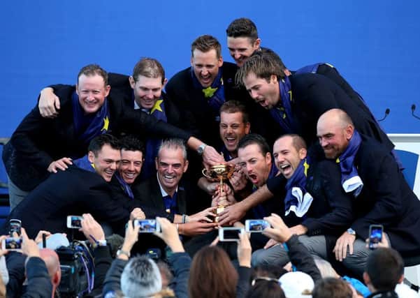 Europes victorious Ryder Cup team, including captain Paul McGinley, front second left, and Lee Westwood, obscured by Victor Dubuisson, top right, with the trophy at Gleneagles last night (Picture: Andrew Milligan/PA).