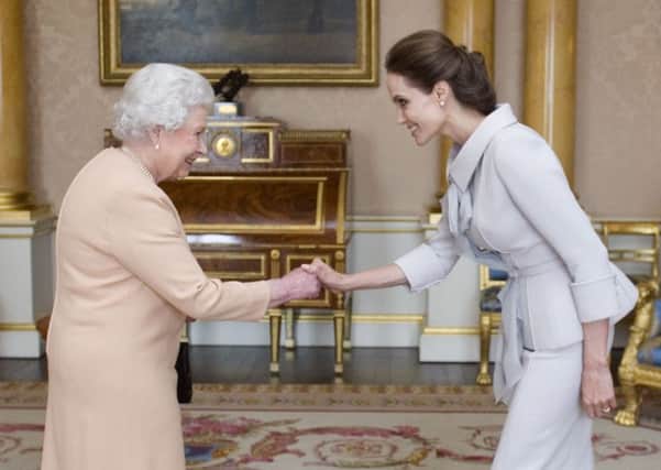Actress Angelina Jolie is presented with the Insignia of an Honorary Dame Grand Cross of the Most Distinguished Order of St Michael and St George by the Queen Elizabeth