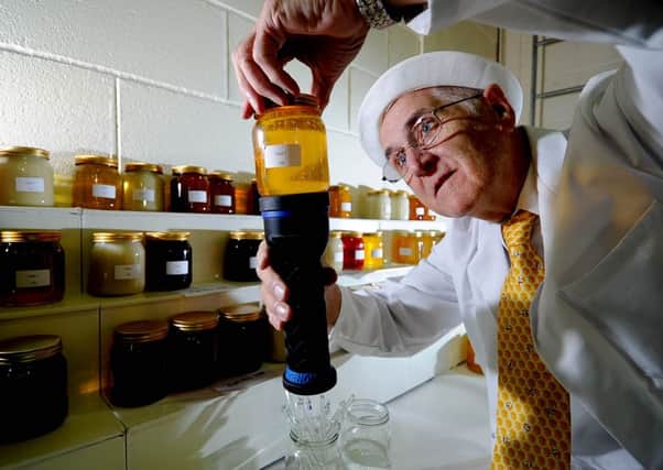 Judge, Bernard Diaper, checking a jar of Liquid Flower Honey.