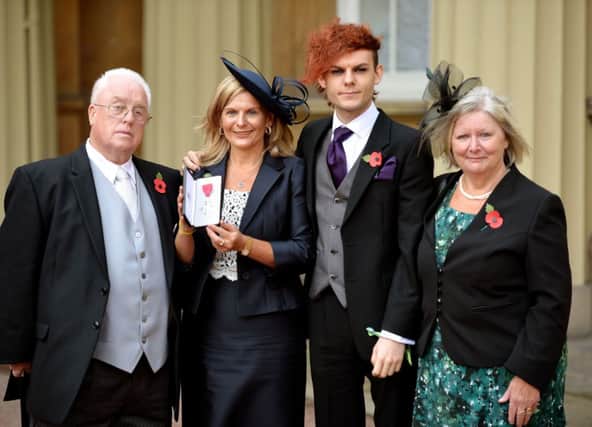 Jane Sutton proudly holds the MBE (Member of the Order of the British Empire (MBE) medal, that was awarded to her son Stephen, with his Grandparents Tony and Ann Reeves, and his brother Chris, after the Investiture ceremony at Buckingham Palace, in central London. PRESS ASSOCIATION Photo. Picture date: Tuesday November 11, 2014. See PA story ROYAL Investiture. Photo credit should read: John Stillwell/PA Wire